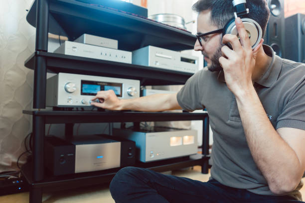 Man turning up the volume on home Hi-Fi stereo Man turning up the volume on home Hi-Fi stereo for louder music stereo photos stock pictures, royalty-free photos & images