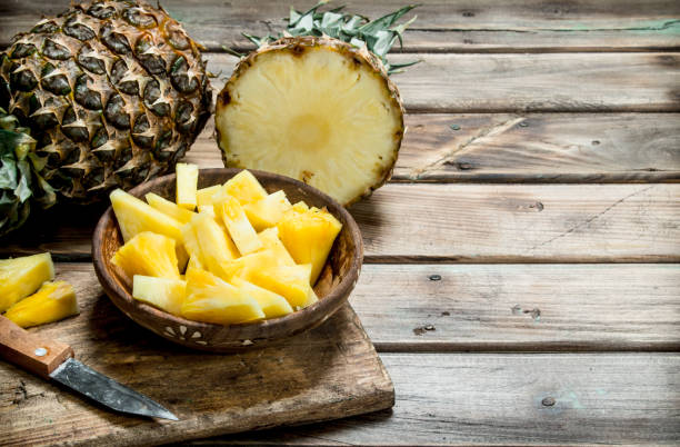 istock Sliced pineapple in a bowl on a cutting Board with a knife and a whole pineapple. 1141486349
