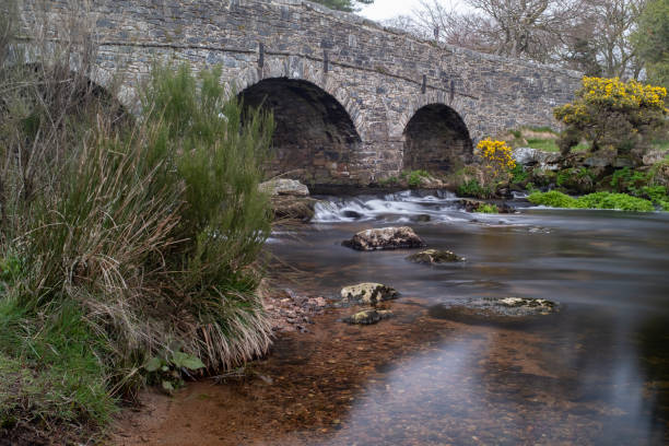 istock View down the river Postbridge, Dartmoor, Devon of a 13th Century granite bridge in the background, long exposure to smooth out the tumbling water 1141489516
