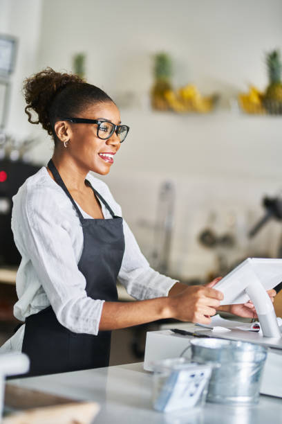istock friendly african american shop assistant using pos terminal to input orders at restaurant 1141491870