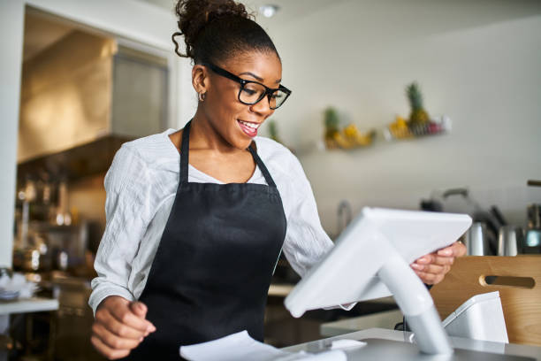 istock friendly african american shop assistant using pos terminal to input orders at restaurant 1141491950
