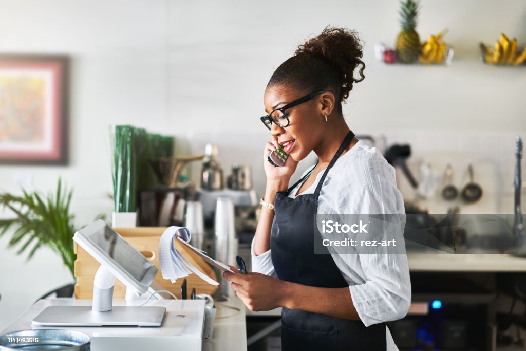 friendly waitress taking order on phone at restaurant and writing on notepad friendly waitress taking order on phone at restaurant and writing on notepad during the day Small Business Stock Photo