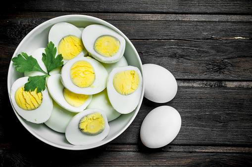 Boiled eggs in a bowl with parsley. On a wooden background.