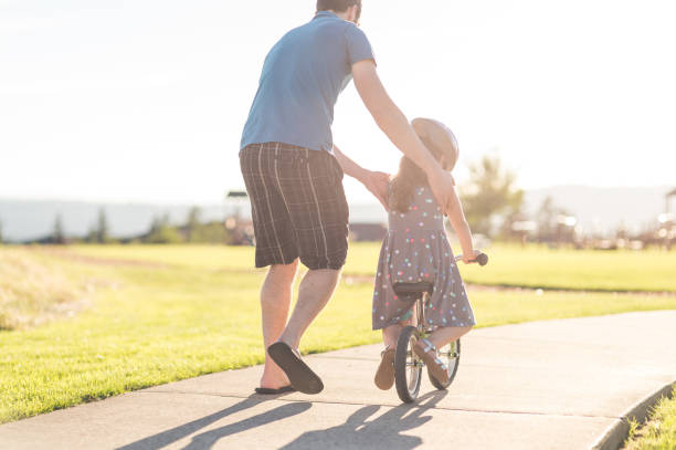 istock Dad helping his daughter learn to ride a bike 1141495907
