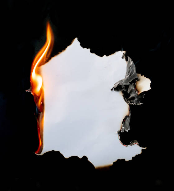 brennendes stück papier auf schwarzem hintergrund - brennen fotos stock-fotos und bilder