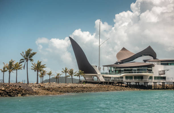 Iconic Yacht Club House, Hamilton Island, Australia. Hamilton Island, Australia - February 16, 2019: Black and white Iconic Yacht Club House behind azure water and under blue sky with white cloudscape. unesco organised group stock pictures, royalty-free photos & images