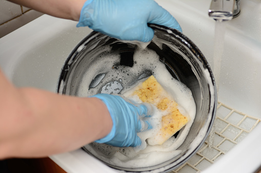 Female hands in rubber protective gloves wash the dishes a sponge with foam