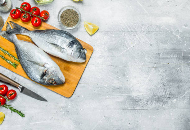 istock Raw sea fish dorado with spices and tomatoes. 1141517338