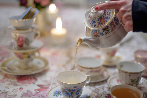 Closeup of woman pouring tea into vintage teacup stock photo