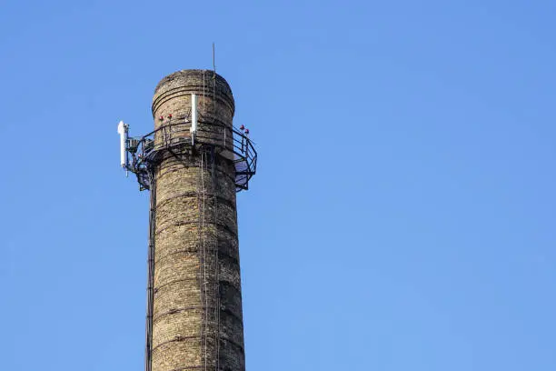 a chimney with electronic communications equipment on it on a blue sky background