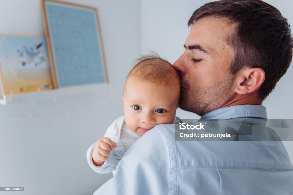 Love to spend time together Father carrying baby son in bedroom, they share moment of love 2-5 Months Stock Photo