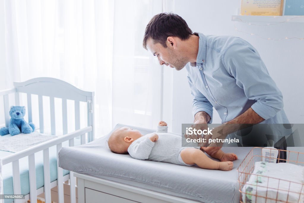 Diaper changing Father change diapers to baby boy on baby changing mat Changing Diaper Stock Photo