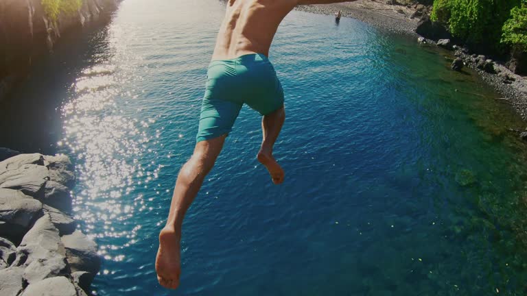 POV shot of young adventurous man jumping into beautiful ocean pool