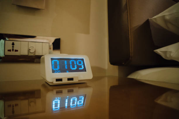 Electronic alarm clock stands on a bedside table in the room