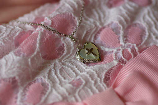 Closeup of baby's gold cross locket necklace on baptism day