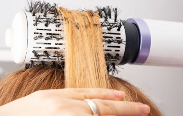 la fille redresse ses cheveux avec un séchoir à brosse volumebrush. curl rouge de cheveu vissé sur une brosse - ringlet photos et images de collection