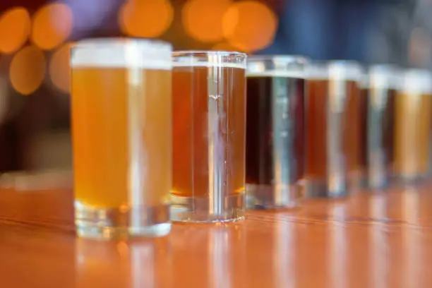 Low angle close up of beer flight lined up on the table at a bar