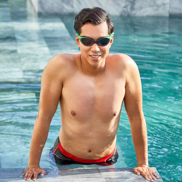istock Young man swimming in pool at resort 1141526711