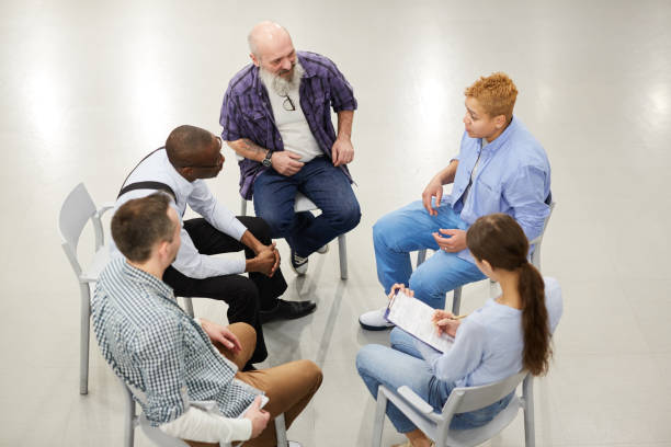 Group Discussion High angle portrait of people sitting in circle during therapy session in support group, copy space alcoholics anonymous photos stock pictures, royalty-free photos & images