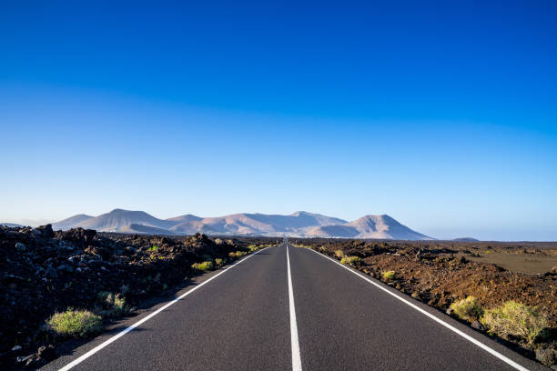 istock Spain, Lanzarote, Magical infinite bolt upright asphalt route alongside lava fields 1141528608