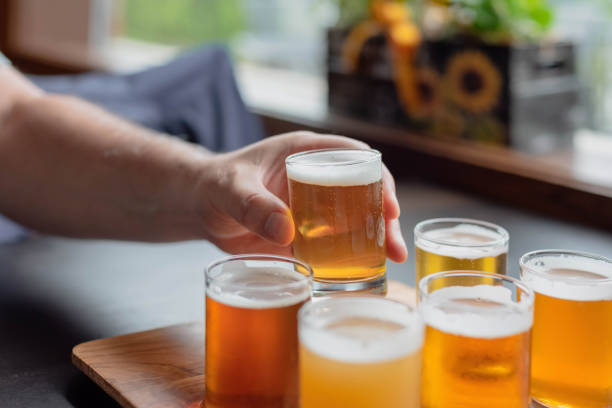 Man’s hand lifting glass from a beer flight stock photo