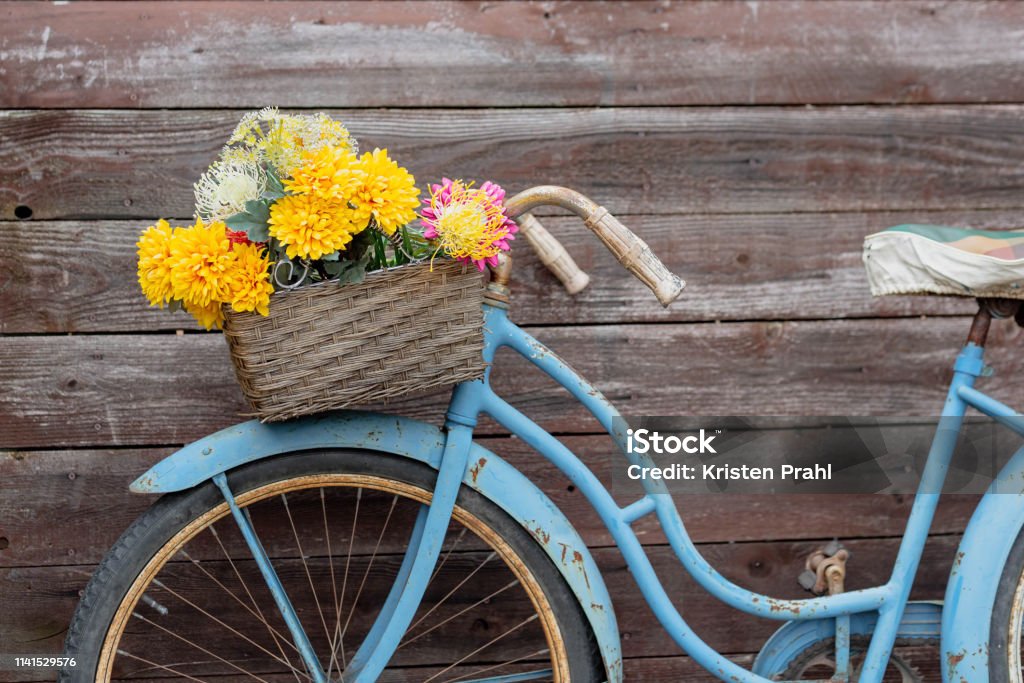 Retro style bike with basket of flowers Vintage blue bike with basket of flowers on wood background Bicycle Stock Photo