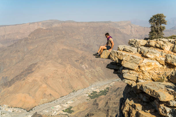istock Man sitting on cliff in desert, Oman 1141529893