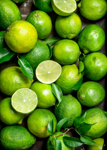 fresca lima jugosa con hojas. - limones verdes fotografías e imágenes de stock