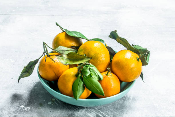 istock Fresh mandarins with leaves in a bowl. 1141531296