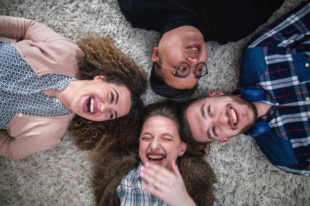 istock Cheerful smiling group of young people lying on a carpet 1141532615