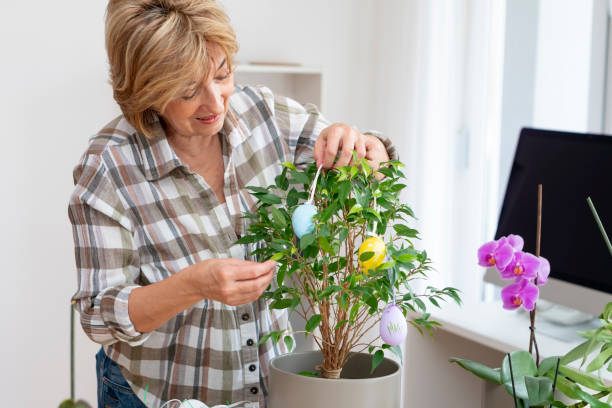 istock Senior woman decorating potted plant with Easter eggs 1141532759