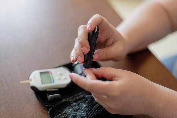 primer plano de la mujer joven pinchando el dedo para probar el azúcar en la sangre - diabetes human pregnancy women blood sugar test fotografías e imágenes de stock