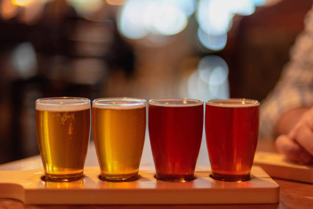 Craft beer flight on wooden paddle Glasses of craft beer lined up on the table at a restaurant craft beer photos stock pictures, royalty-free photos & images