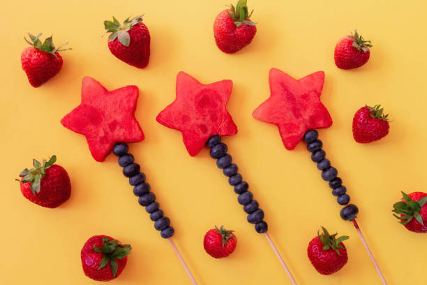 istock Star shaped fruit kabobs on bright yellow background - fresh summer foods 1141534344
