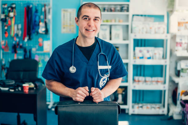 Portrait of a happy veterinarian Smiling veterinarian with stethoscope, holding leather doctor's bag in vet clinic leather medical bag stock pictures, royalty-free photos & images