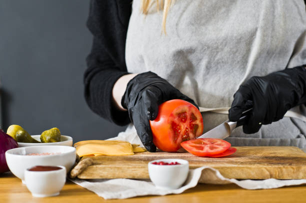 istock Chef cuts red tomatoes. The concept of cooking a black Burger. Kitchen, side view, space for text. 1141535976