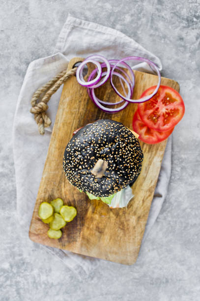 Juicy double black Burger on a wooden chopping Board. Top view, gray background, space for text.