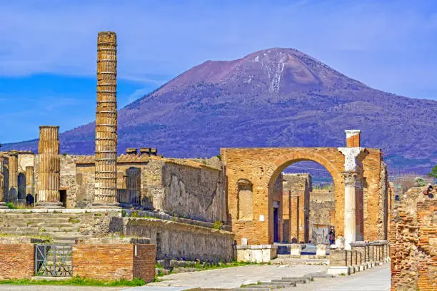 Temple columns and gate with Vesuvius volcano in the background  at the ancient Roman city of Pompeii, Italy