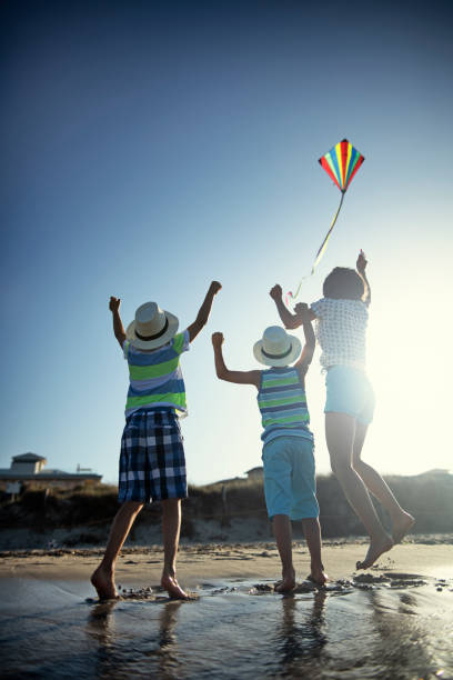 istock Kids flying a kite on a beach 1141541005