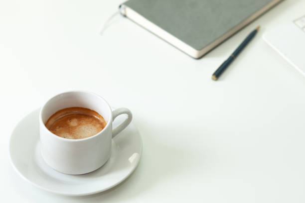 кофейная чашка, ноутбук и серая нотпада на белом столе. селективный фокус. - notpad стоковые фото и изображения