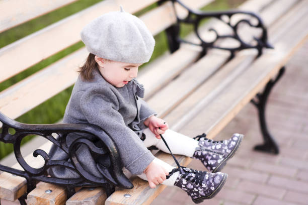 Baby girl in park Baby girl lace shoes sitting on bench in park. Wearing french style beret and coat. Childhood. kids winter fashion stock pictures, royalty-free photos & images