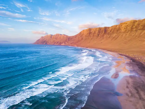 Famara Atlantic ocean beach surf spot aerial view  of scenic landscape from drone in Lanzarote, Canary islands during warm sunny summer day, vacation holidays destination for surfing near La Santa