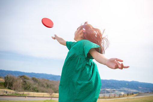 Little girl throwing disc to the sky