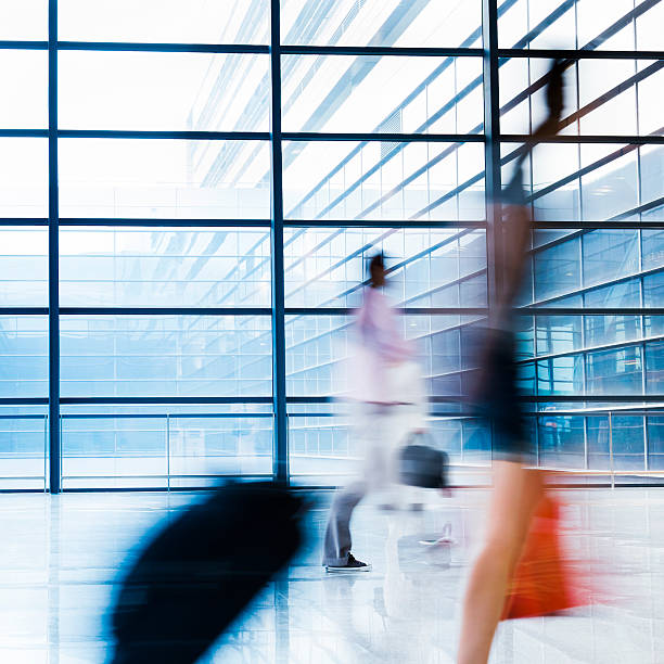 istock Blurred Travellers Pulling Suitcase Along Hallway in Airport 114155398