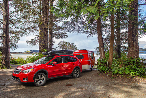 Red car and retro trailer, Vancouver Island, BC, Canada - May 10, 2018: Car camping with antique tiny trailer.
