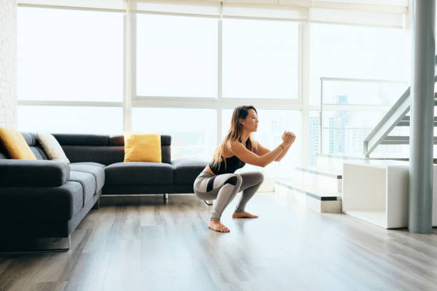 Adult Woman Training Legs Doing In and Out Squat Fit young Pacific Islander woman training at home. Beautiful female athlete working out for wellbeing in domestic gym, training legs muscles with in and out squats. woman legs open stock pictures, royalty-free photos & images