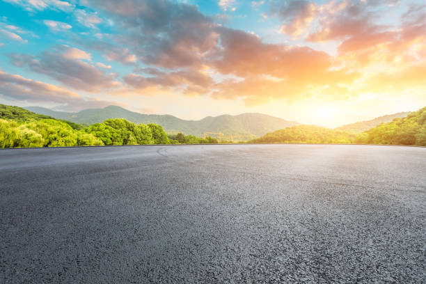 pista de asfalto y montañas con hermosas nubes al atardecer - traffic car street parking fotografías e imágenes de stock