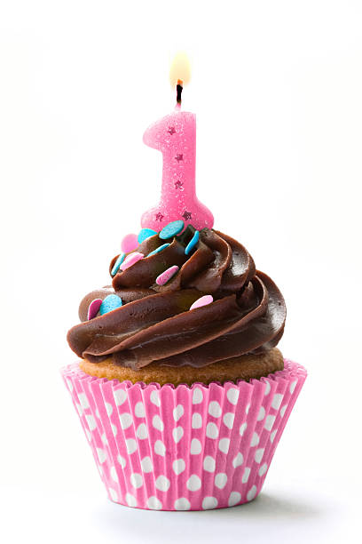a birthday cupcake with the number one and chocolate icing - eerste verjaardag stockfoto's en -beelden