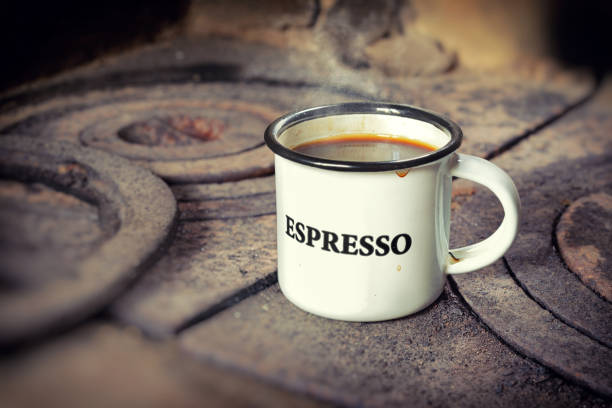 Old-fashion enamel cup with espresso coffee on the old rusty wood-burning stove