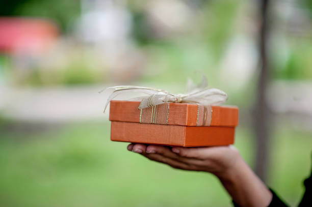 istock Hand and orange gift boxes give to your loved ones. Gift ideas 1141587928